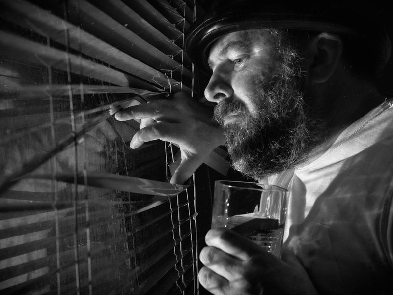 Person looking into the distance near a large window.